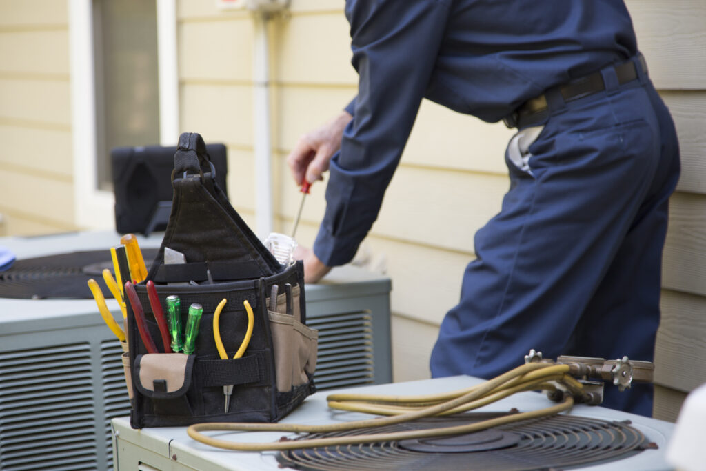 Tools sitting on top of HVAC unit with technician working in the background.