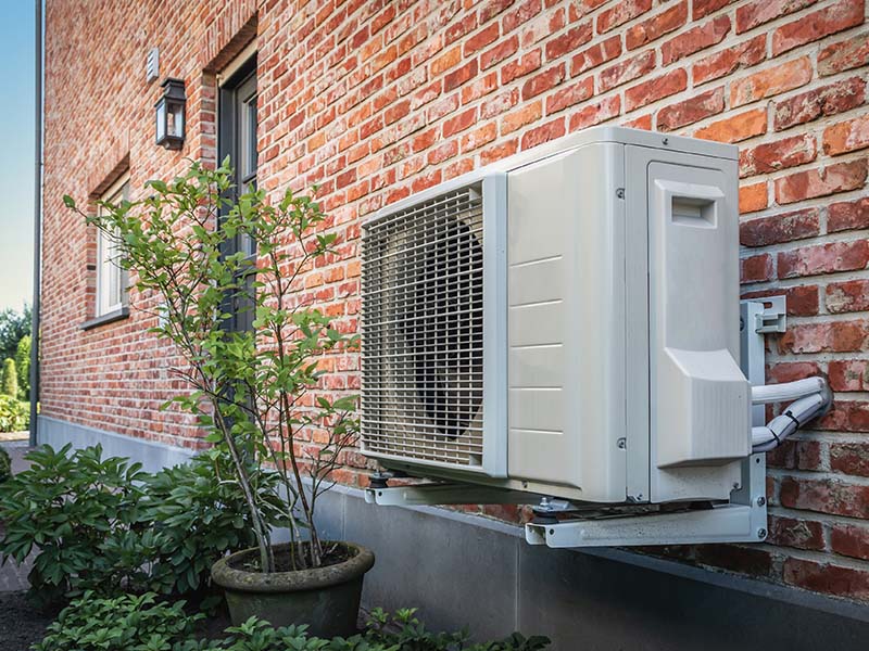 New heat pump installed outside of a brick home.